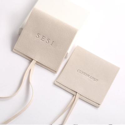 China Protect Jewelry Custom Printed Logo Microfiber Envelope Earring Ring Gift Jewelry Beige Deboss Pouch With Ribbon for sale