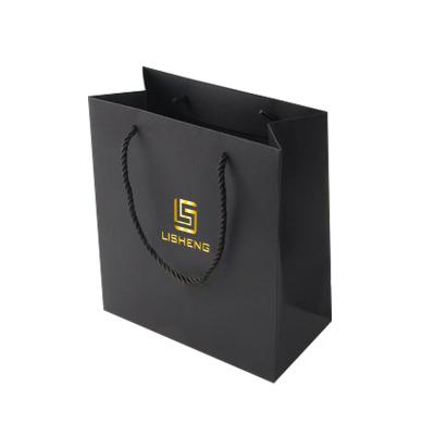 China Recycled Material Custom Printed 250g Matte Black Gold Foil Suitcase Clothing Shopping Paper Bag With Twisted Handle for sale