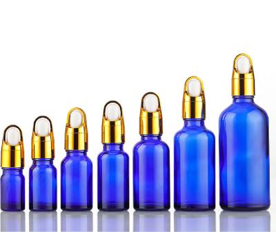 China 10ml 30ml 50ml Essential Oil Glass Cosmetic Blue Bottle With Gold Flower Basket Cover Lid Dropper for sale