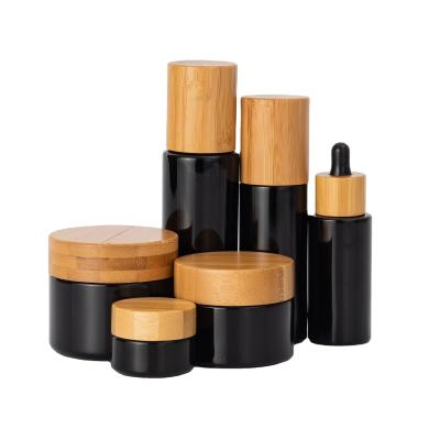 China Cosmetic dark violet glass bottles and black jars and jars bottles with bamboo lid for sale