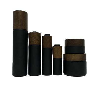 China Bamboo Matte Black Glass Bottles And Jars Personal Care With Ash Tree Fillings Cosmetic Glass Bottle for sale