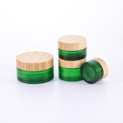 China Hot Selling Personal Care Cosmetic Glass Jar Frosted 50g 100g Green Glass Cream Jar With Bamboo Lids for sale