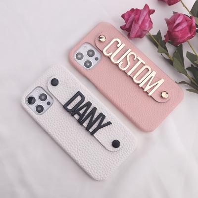 China Custom Leather Stand Shockproof Gold Name Strap/Black Big Metal Letter Phone Case For iPhone13 14 Pro Max Phone Cover for sale