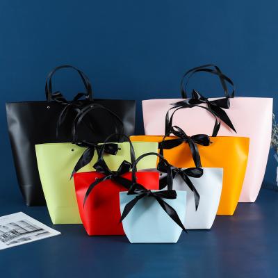 China Boutique Biodegradable Wholesale Glosy Folding Shopping Paper Bag With Ribbon Gift Cosmetic Bags Custom Logo for sale