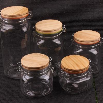 China Sustainable Glass Honey Mason Jar With Clip Lid Square Glass Storage Jar With Lid And Wooden Spoon for sale