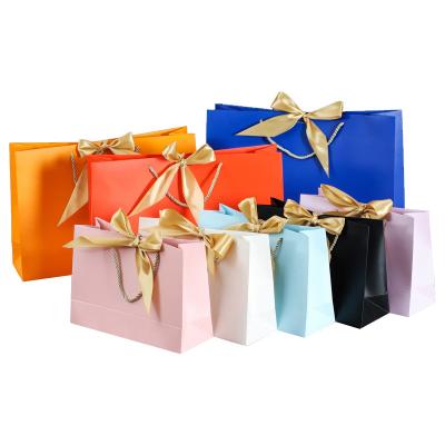 China Recyclable Pink White Blue Orange Garment Makeup Cosmetic Gift Paper Bag With Ribbon Bow for sale