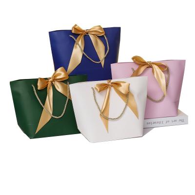 China Recycled Materials Bow Paper Bag Wholesale New Year Gift Clothing Bow Paper Bag Women Clothing Store Cosmetic Shopping Bag Small for sale