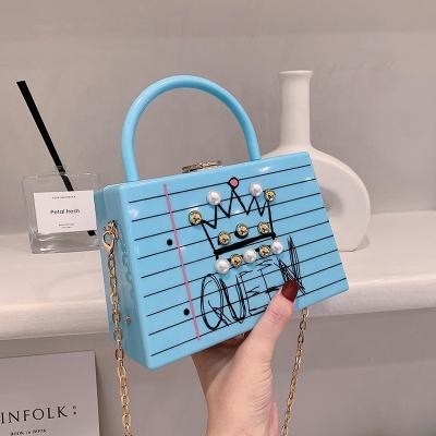 China 2021 Motion Detection 2021 Motion Detection Fashion Hand Ladies Acrylic Handbags Ladies Black Queen Text PVC Cross Chain Tiny Bag for sale