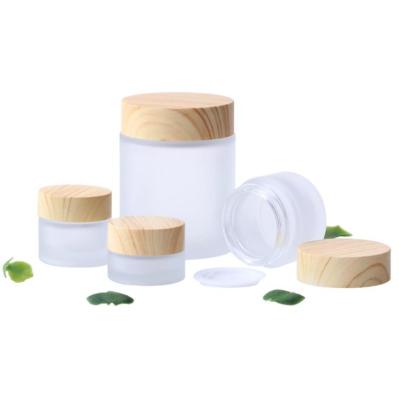 China 5g cosmetic 10g 15g 30g 50g 100g frosted clear glass cream jar with wood grain cap for eye/face cream for sale