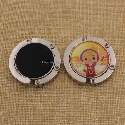 China Eco-friendly Custom Logo Printed Metal Purse Hanger /Round Bag Hanger With Soft Epoxy for sale