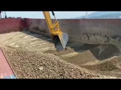 The long arm of the excavator is used for unloading at the dock