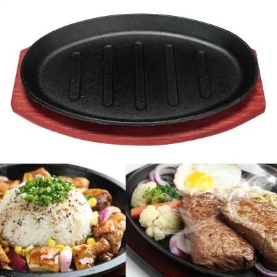 China Gegote ijzeren ovale vorm Szizzling Plaat Frying Pan Steak Platen met houten basisplaat Te koop