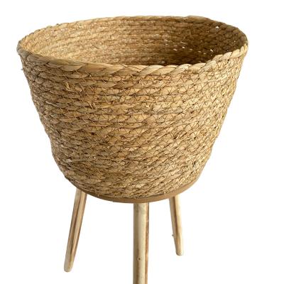 China Modern Natural Woven Plant Fiber Design Flower Potted Plant Pot 100% Straw Basket With Wooden Legs for sale