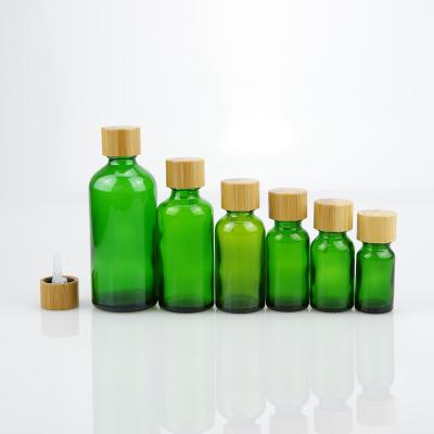 China 18/415 cosmetic wholesale bamboo screw cap for 5ml 10ml 15ml 20ml 30ml 50ml 100ml essential oil glass green bottle for sale