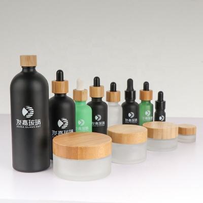 China Personal Care Logo Printed 15g 30g Frosted Green Cosmetic Essential Oil Dropper 1oz 2oz 50g 100g Glass Jars With Bamboo Wooden Lids for sale