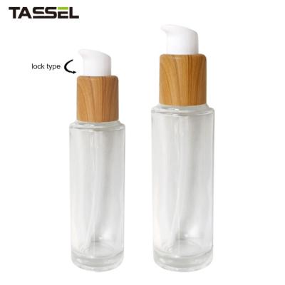 China 30ml 50ml Round Glass Bottle With Wooden Effect Treatment Pump Lock Type for sale