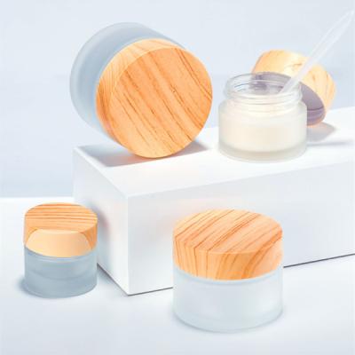 China Cosmetic glass packaging for cosmetics empty jars round 30ml 50ml frosted glass cosmetic cream jar with wood grain lid for sale