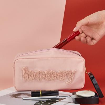 China Fashion Plush Letters Honey Travel Cosmetic Bag With Pink Zipper Nylon Waterproof Cosmetic Bags for sale