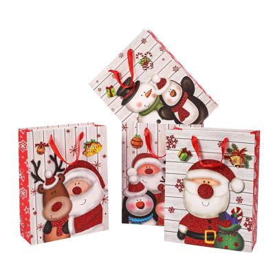 China Recycled Materials Glitter Powder Pattern Christmas Paper Bags Package Santa Claus Customized Christmas Cartoon Shopping Paper Bag With Handles for sale