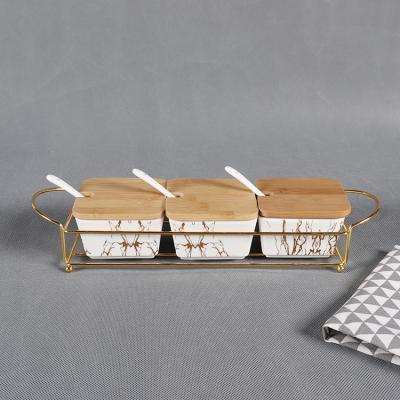 China Viable Custom Design Ceramic Gold Decal Kitchen Spice Set With Lid Spoon And Wooden Metal Rack for sale