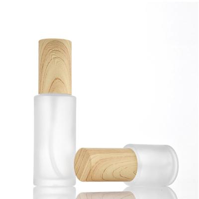 China Cosmetic in the press pump bottle stock lotion bottle frosted cosmetic glass bottle with wood grain cap for sale