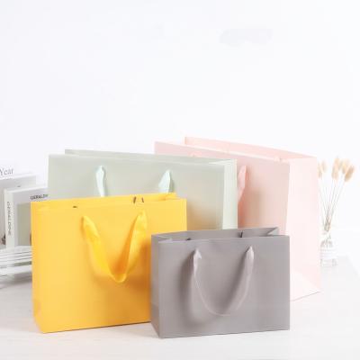 China Biodegradable Makers Spot Apparel Gift Shop Creative White Cardboard Paper Packaging Portable Paper Bag for sale