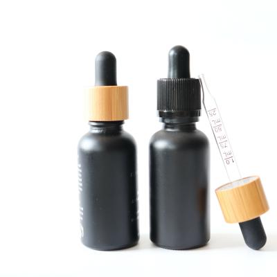 China 30ml cbd oil bottle pharmaceutical wholesale empty black frosted glass bottle with bamboo wooden cap for sale