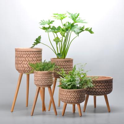 China Eco-friendly creative handcrafted relieved rattan pattern round shape cement plant flower pots with three bamboo legs for sale