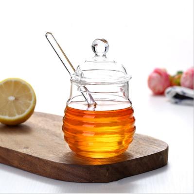 China Unique Empty Round Shape Hive Style Clear Borosilicate Food Grade Design Honey Jar Glass With Dipper And Lid for sale