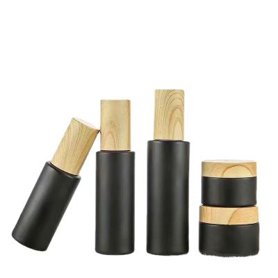 China Wholesale Matte Black Glass Bottle Color 50ml Spray Bottle Lotion Pump Cosmetic Glass Bottle With Wooden Grain Plastic Cap for sale