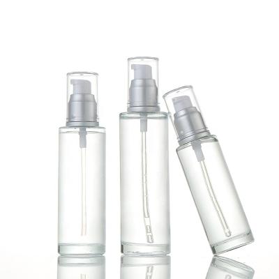 China Cosmetic Lotion Variety Size Flat Shoulder Clear Glass Bottle With Matte Sliver Pump for sale