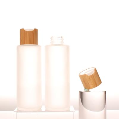 China 100ml Personal Luxury Bamboo Disc Skin Care Cap Frost Glass Bottle Top Shampoo Bottle For Wholesale for sale