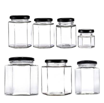 China Hexagonal Clear Amber Glass Honey Freshness Preservation Candle Glass Jar Jar With Black Gold Aluminum Metal Lids for sale