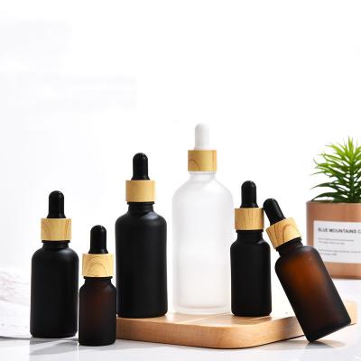 China Hot Selling Personal Skin Care Packaging Bamboo Cap Frosted Black Amber Transparent Glass Essential Oil Dropper Bottle for sale