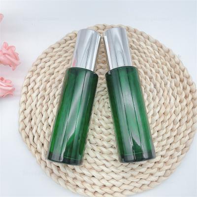 China Perfume 2oz 60ml Custom Empty Glossy Green Cylinder Glass Bottle With Lotion Pumps for sale