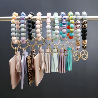 China Silicone Bracelet Wrist Key Chain PU Tassel Cards Case Eco-friendly Female Pearl Bracelet Key Ring for sale