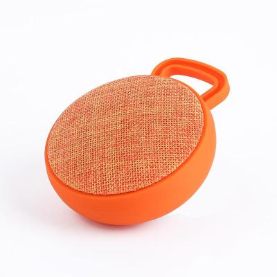 China Portable Mini Wireless Outdoor Cloth Music Cloth Music Speaker Professional Sports Round Wireless Speaker with Plastic Button Panel and Handle for sale