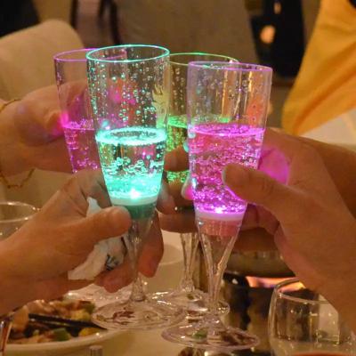 China Custom LED Party Supplies Liquid Active Flute Glowing In Dark Cup Replaceable Battery Dishwasher Safe LED Light Up Wine Drinking Glass for sale