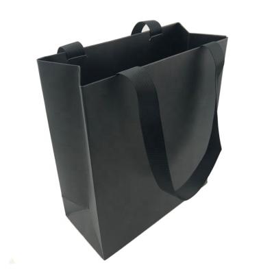 China Recyclable Elegant Art Paper Printed Matte Black Paper Bag With Ribbon Handle for sale