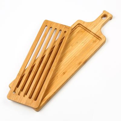 China Sustainable Design Long Strip Bamboo Bread Cutting Board with Handle and Slotted Bread Paddle Serving Board with Crumb Catcher Grid for sale