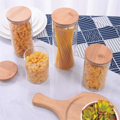 China Freshness Keeping Kitchen Different Sizes Tube Shaped Storage Glass Jar With Bamboo Wooden Lid for sale