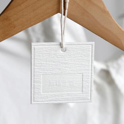 China Luxury Custom Recyled Jeans Embossed Own Name Logo Cardboard Swing String Loop White Paper Hang Tags For Clothing for sale