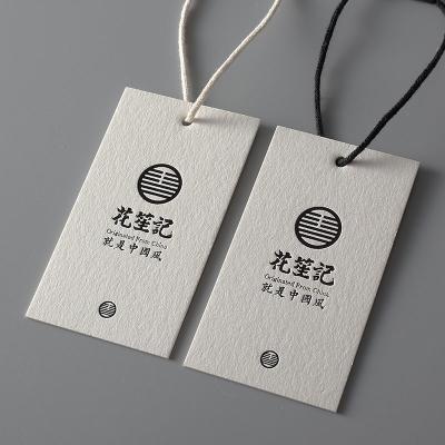 China Viable Accessories Factory Custom Swing Hang Tag Label Embossed Logo White Matte Paper Clothing Hang Tag for sale