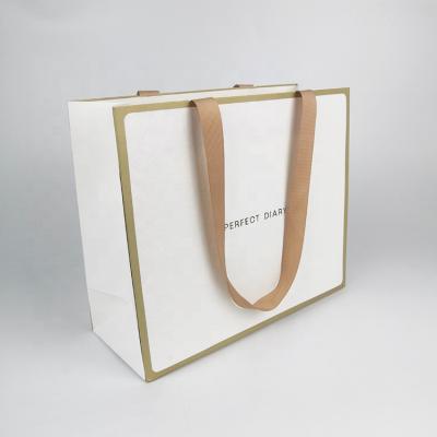 China Recycled White Paper Shopping Gold Border Cardboard Personal Custom Classic Clothing Materials Gift Bag With Gold Ribbon Handle for sale