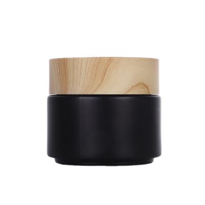 China Sustainable Hot Sale Cosmetic Cream Matte Black Glass Jar With Bamboo Wooden Lids for sale