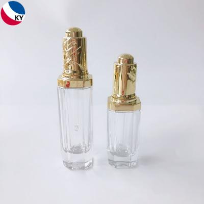 China 30ml 50ml Clear Thick Unique Glass Cosmetic Push Button Cosmetic Pump Dropper Packaging Bottle With Gold Press Dropper for sale