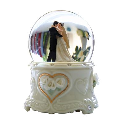 China Europe Custom 100mm Resin Musical Box Wedding Snowball Snow Glass Globe Rotating Figurine Gifts Souvenir Birthday for sale