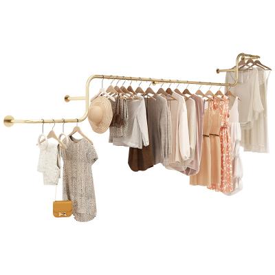 China Clothes Shop Custom Exquisite Decorative Shiny Gold Metal Hanging Shelves For Wall Woman Temperament Cloth Display Stands for sale