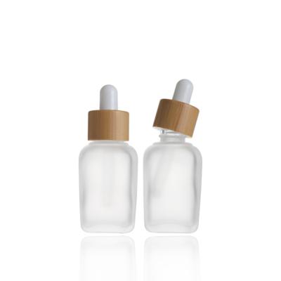 China Personal Care 30ml Flat Shoulder Essential Oil Glass Dropper Bottle With Bamboo Cap Cosmetic Bottle for sale