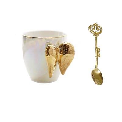 China Sustainable Creative Mug With Gold Wings Handle Gift Mug With Spoon Ceramic Travel Mug for sale